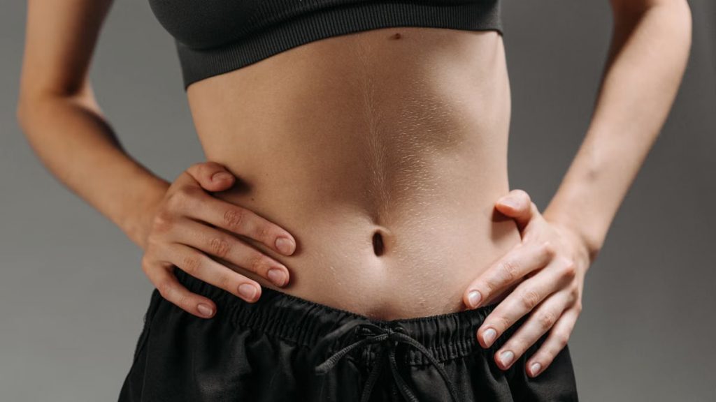 Focused shot of a woman's torso showing athletic physique in a studio setting.